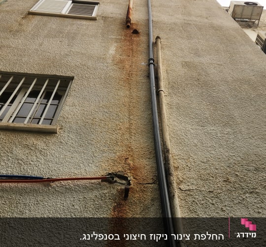 צינורות חיצוניים על קיר בניין עם חלודה